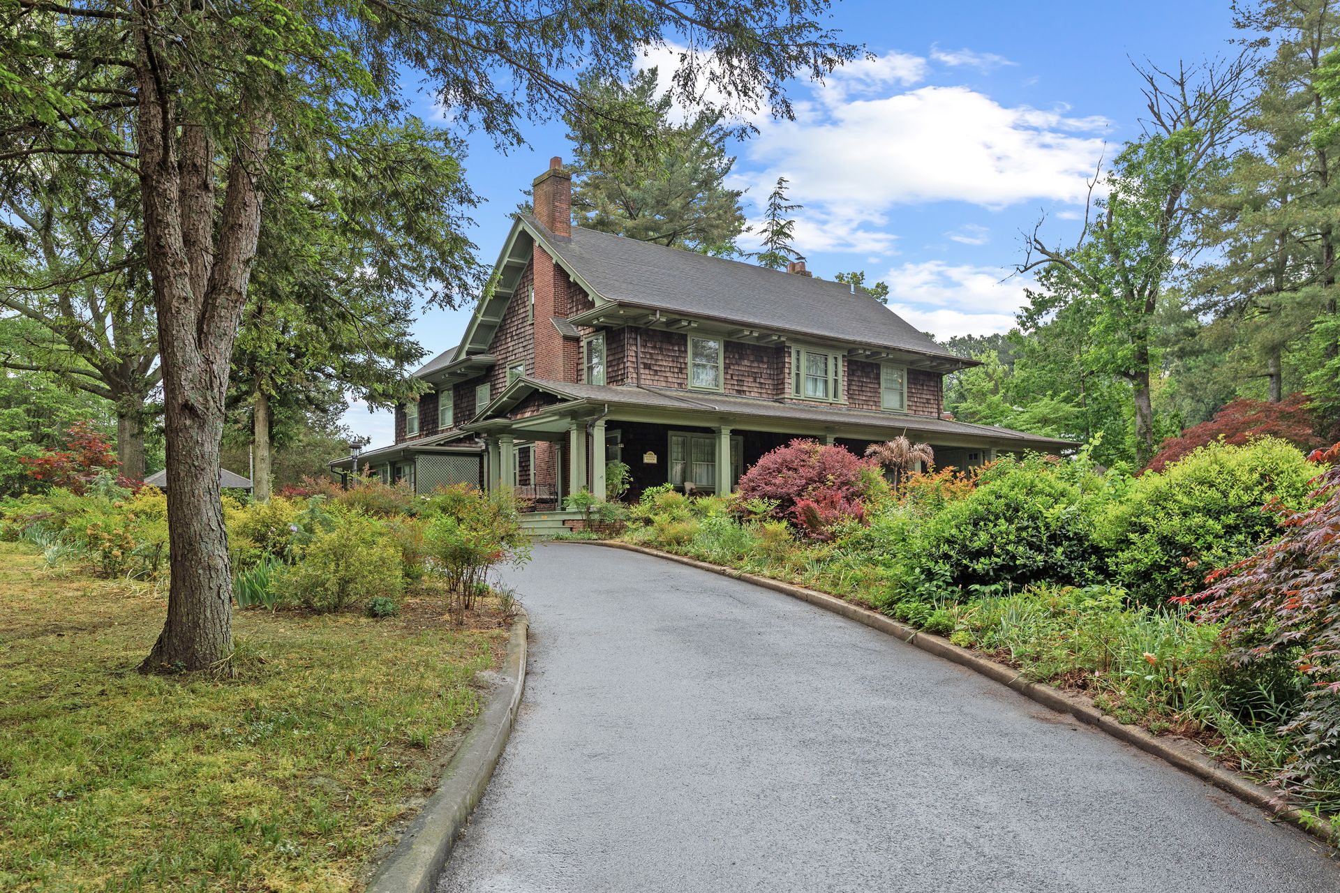 Warwick Manor exterior — a grand Craftsman estate nestled among mature trees with a sweeping driveway