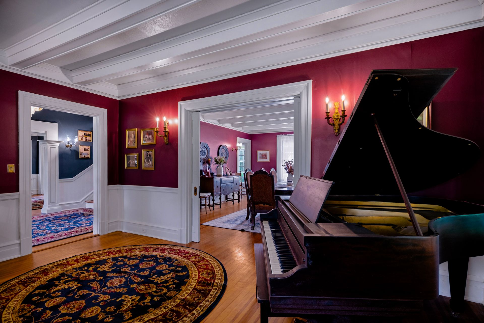 The grand piano room at Warwick Manor with burgundy walls and crystal chandeliers